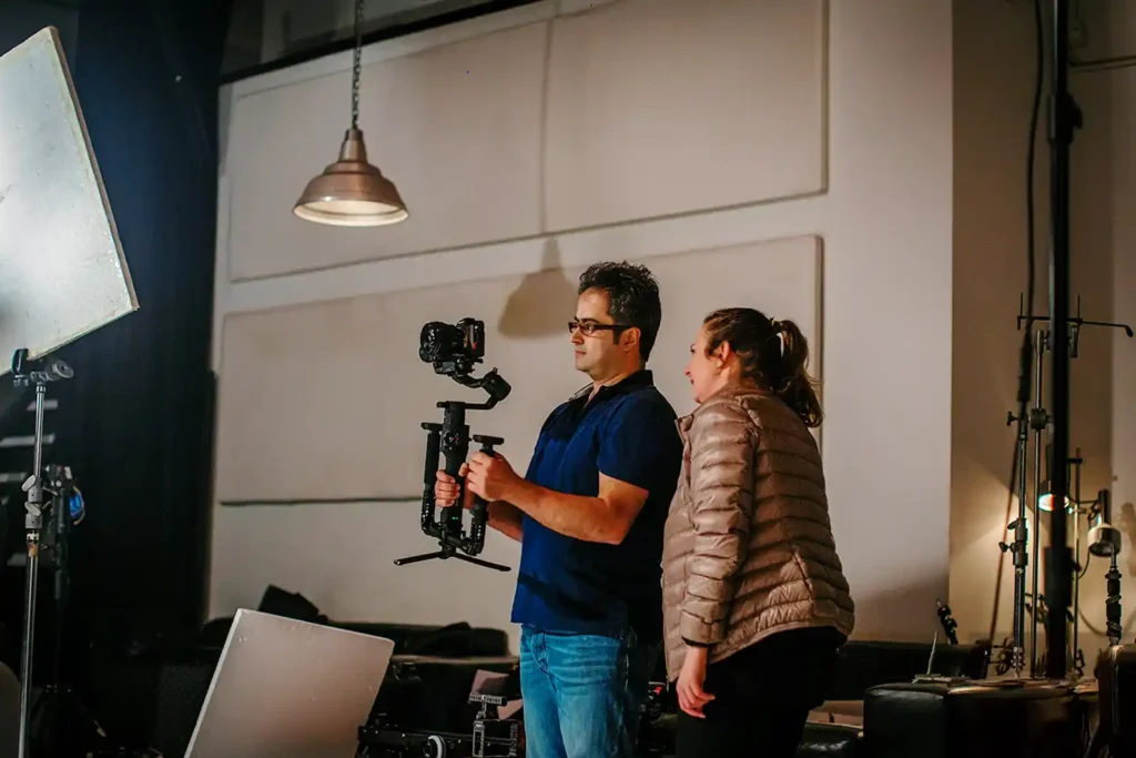 Two members of the HAPfilm NZ Ltd crew review camera setup on set during the filming of Nameh Majnoonan, using professional equipment in a studio with controlled lighting in Auckland, New Zealand.