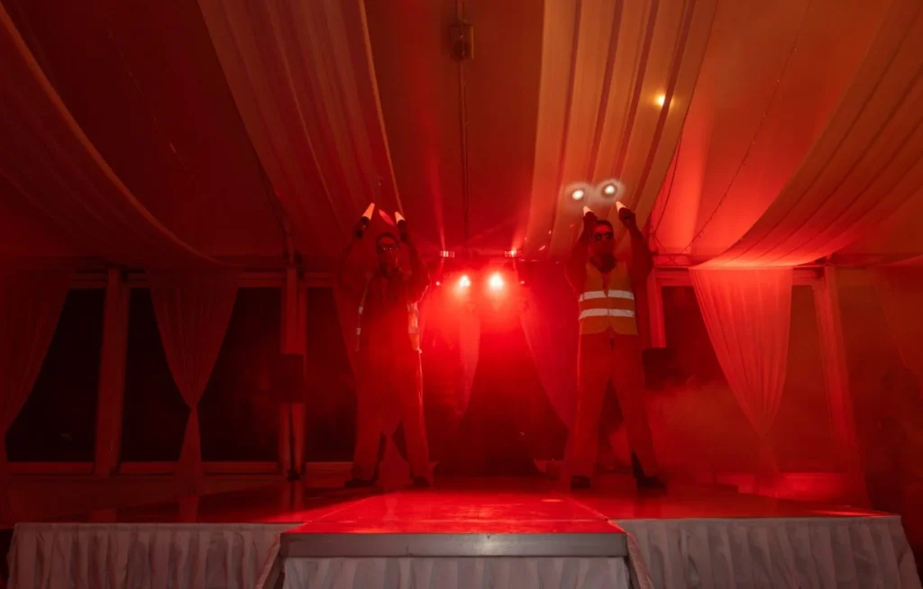 Performers from the Men of Steel event at Allely Estate, illuminated by red stage lighting, delivering a powerful act.