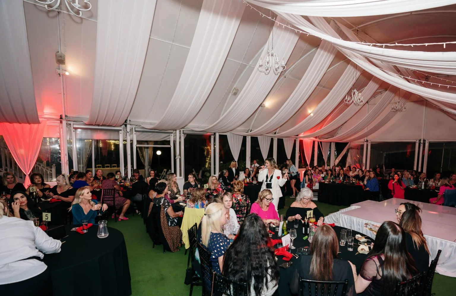 Attendees mingling at Allely Estate during the Men of Steel event, under a canopy of trees and twinkling lights.