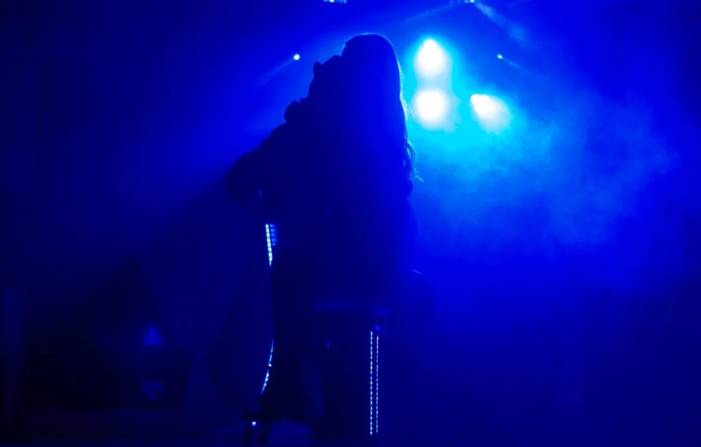 Alicia performing under blue lights at Allely Estate, her silhouette creating a mystical ambiance.