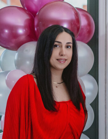Elham, owner of Kiwi Event Decor Auckland, standing confidently in front of a pink and white balloon decor installation.