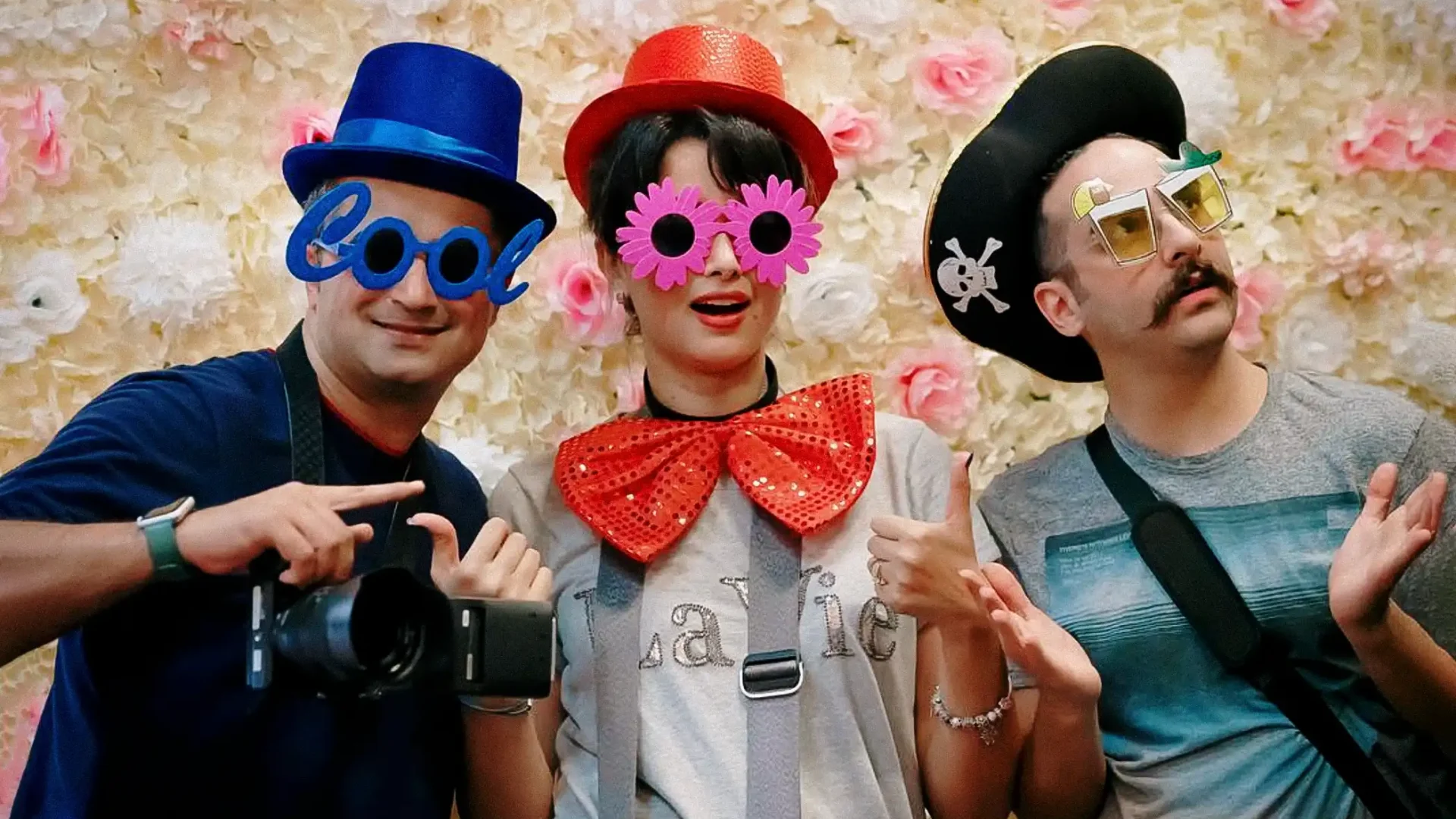 HAPfilm team members in colorful costumes and props at a photo booth during a New Zealand wedding