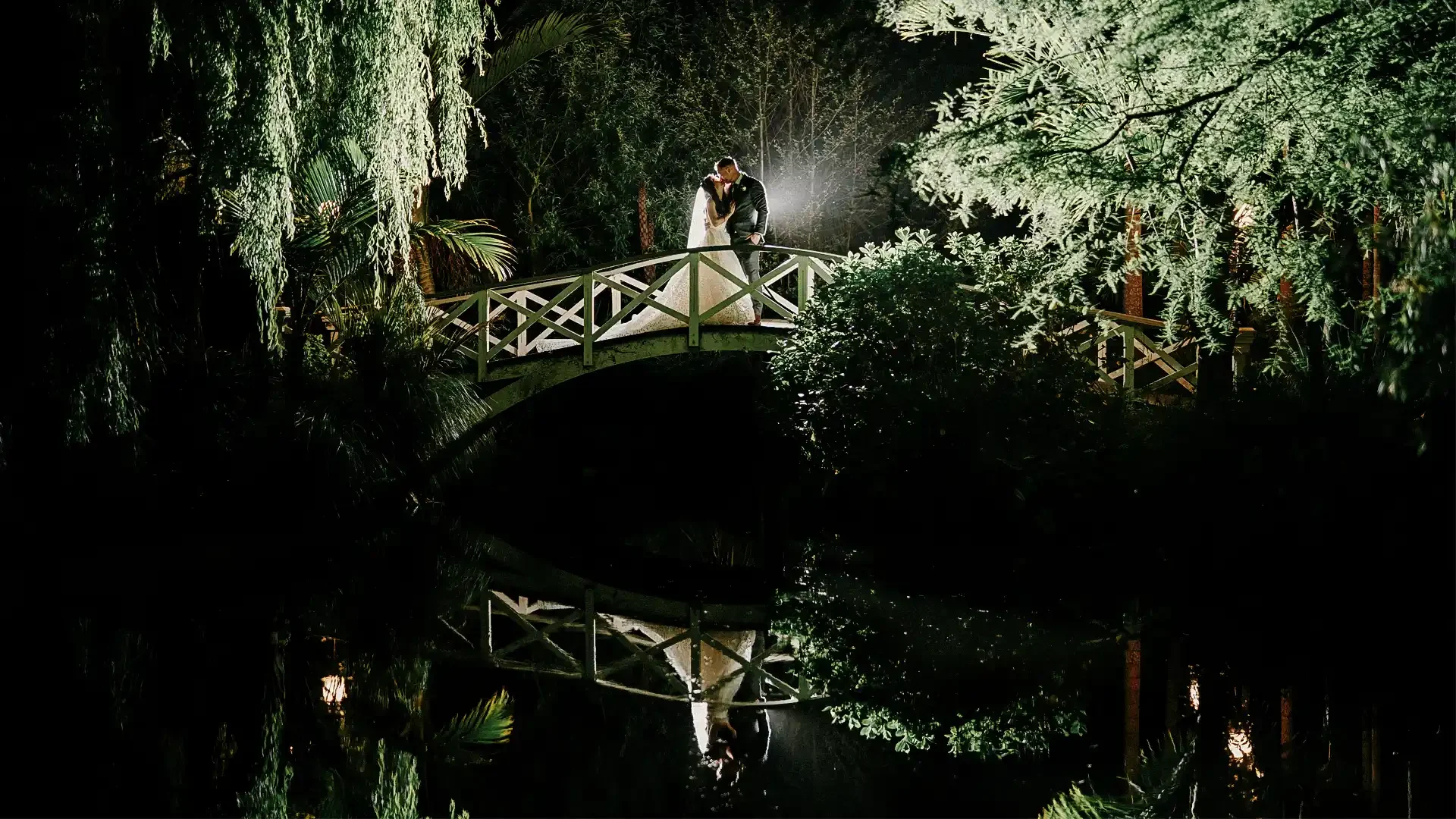 Newlywed couple shares an intimate moment on a beautifully lit bridge at Settlers Country Manor in West Auckland, captured by Hapfilm, one of New Zealand's top wedding photographers